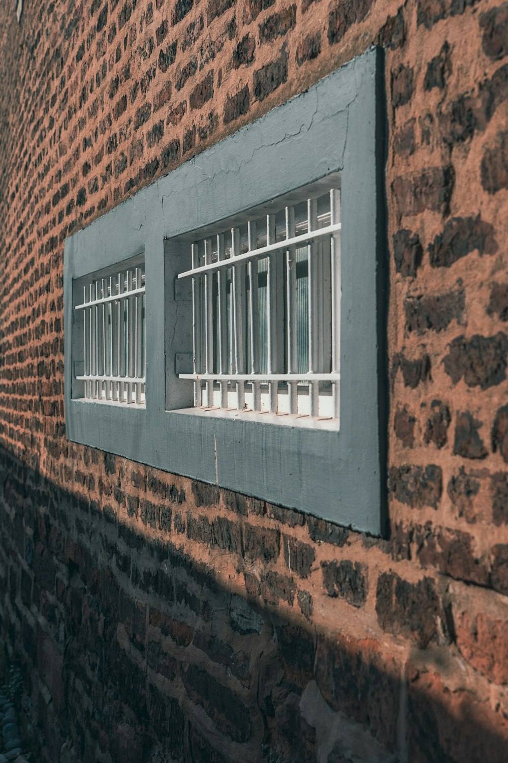 a brick wall with a window and bars on it