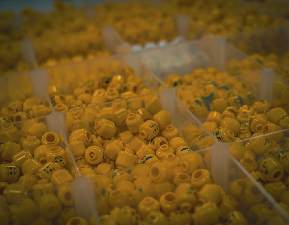 a bunch of yellow beads in plastic containers