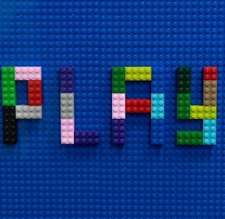 the word play spelled out of legos on a blue surface