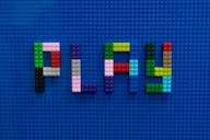 the word play spelled out of legos on a blue surface