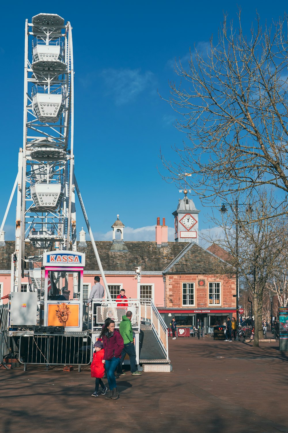 a ferris wheel in a town square with people walking around