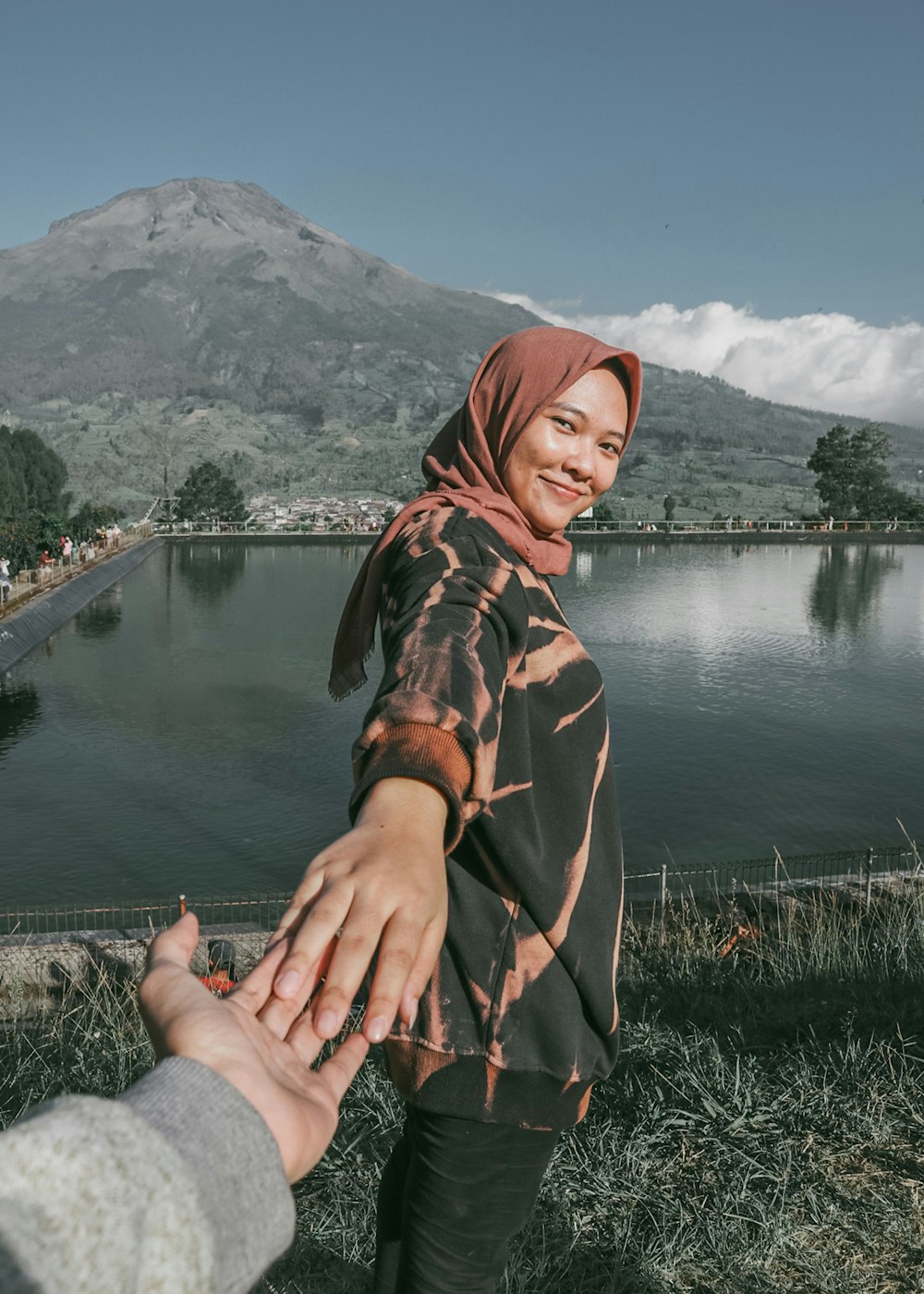 um casal de pessoas de mãos dadas perto de um lago