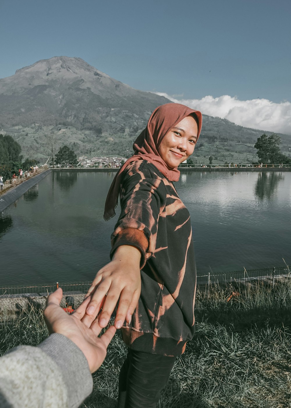 a couple of people holding hands near a lake