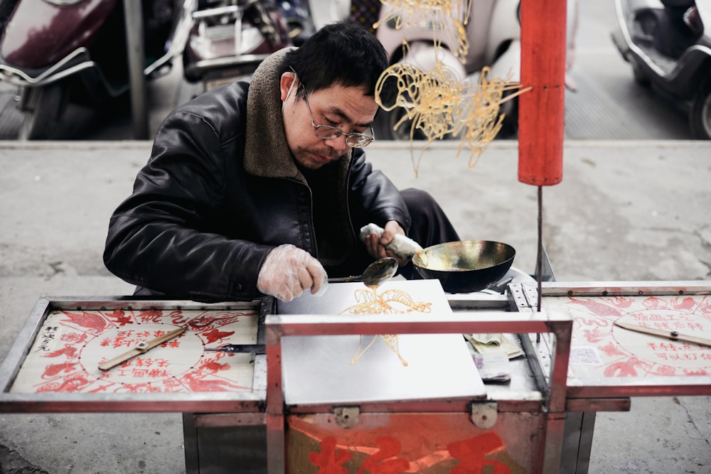 a man sitting at a table with a wok on top of it