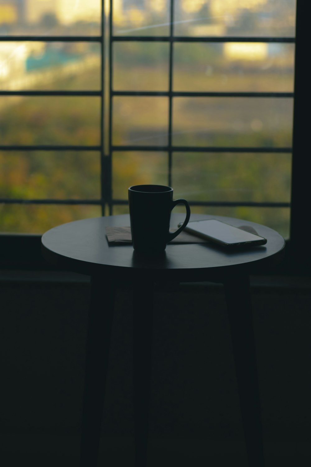 une tasse de café posée sur une table à côté d’une fenêtre