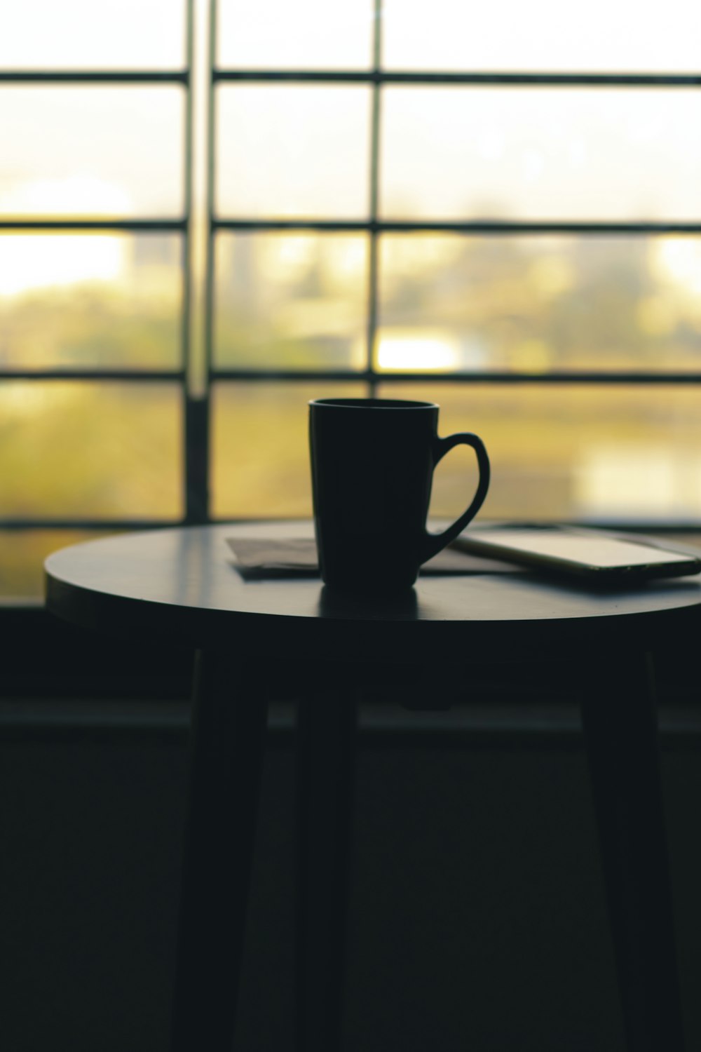 a coffee cup sitting on top of a table next to a window