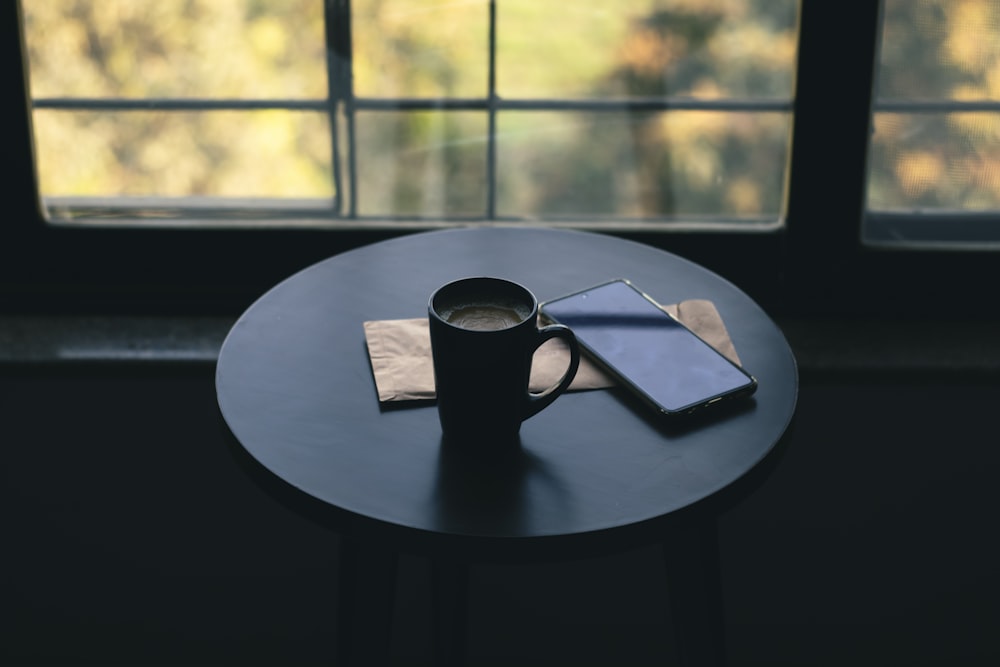 a cup of coffee and a cell phone on a table