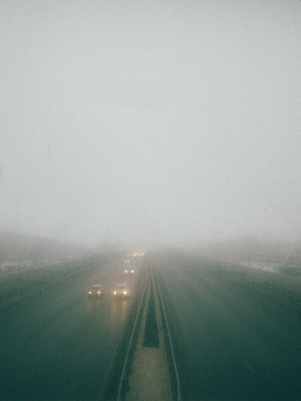 a foggy highway with several cars driving on it