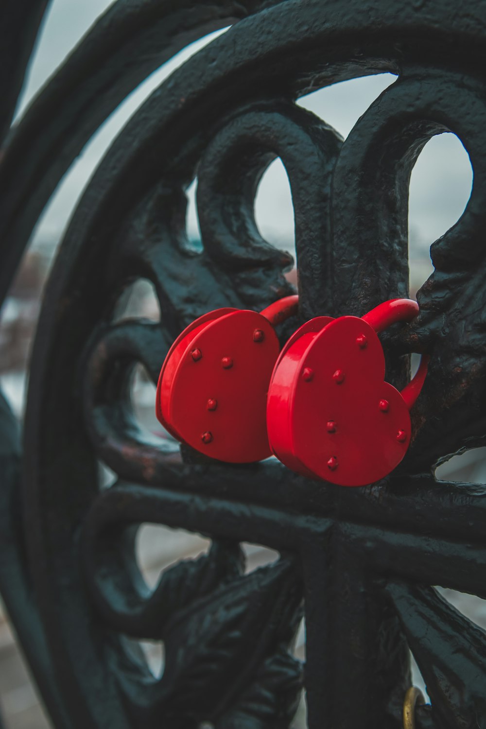 a pair of red hearts are attached to a wrought iron fence
