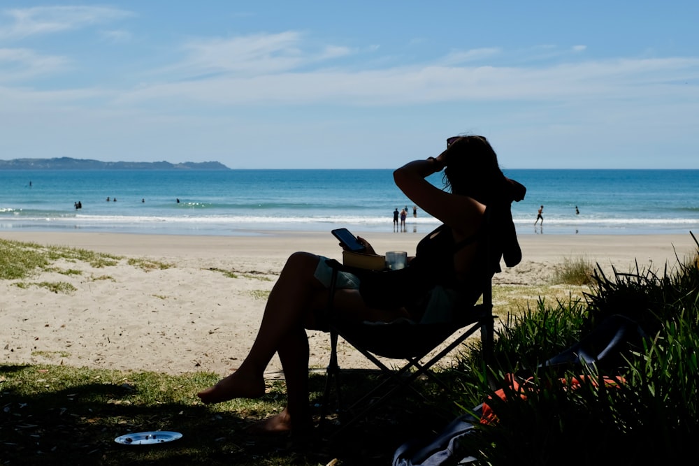 a woman sitting in a chair on the beach