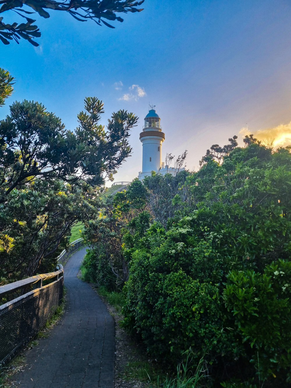 a path leading to a light house surrounded by trees