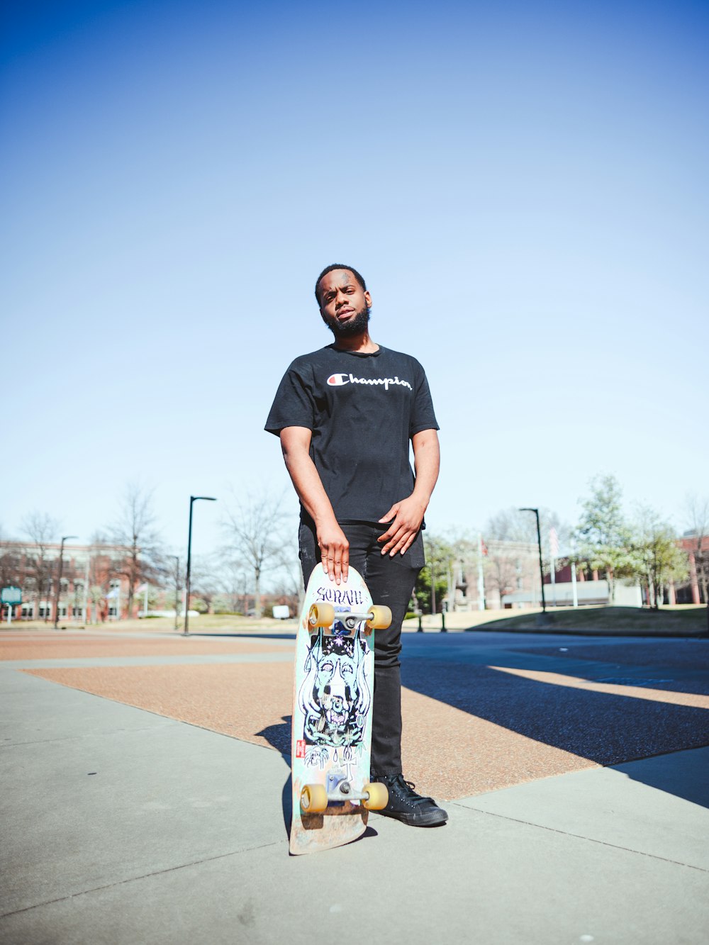 a man holding a skateboard on a sidewalk