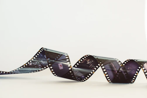 A vibrant film reel unspooling over a collage of black and white photographs