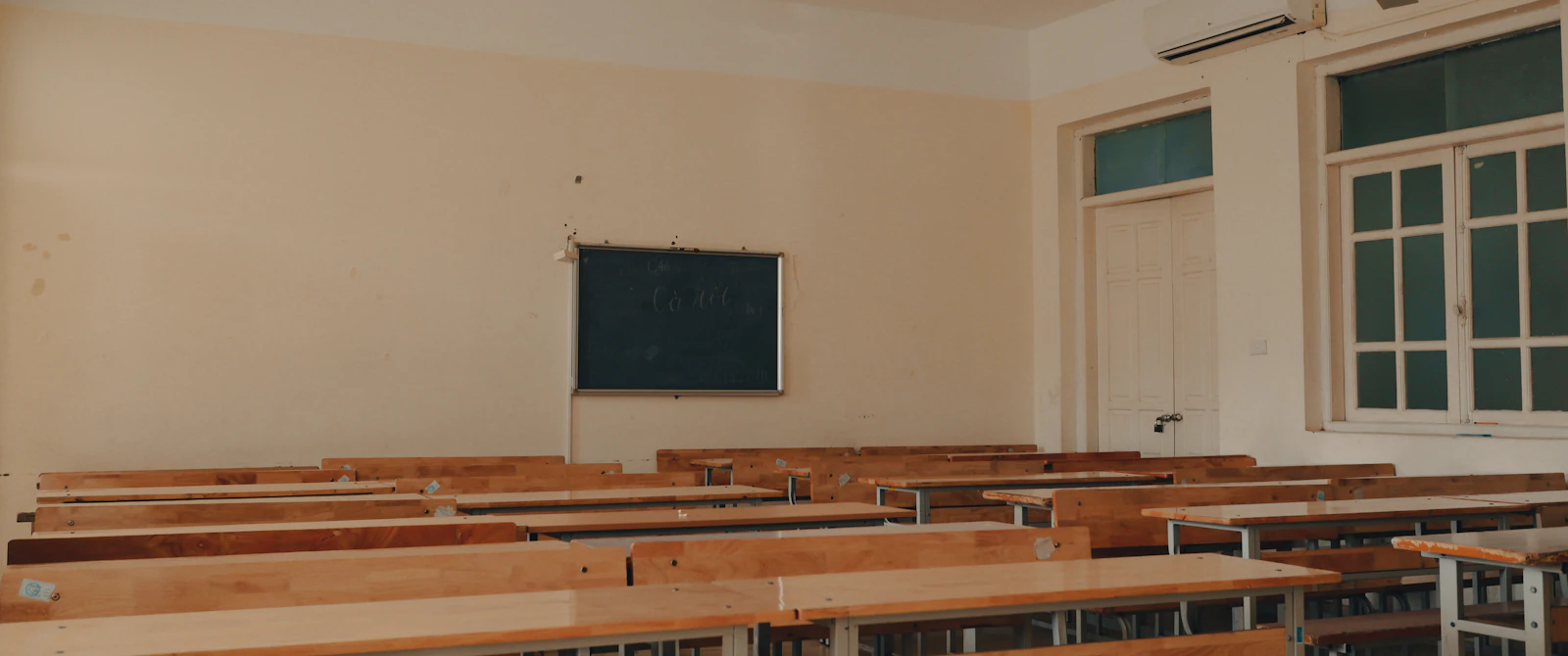 An empty classroom with rows of desks and a chalkboard, the kind of Jamaican secondary school room where CSEC candidates sat, or did not sit, their May/June 2026 papers