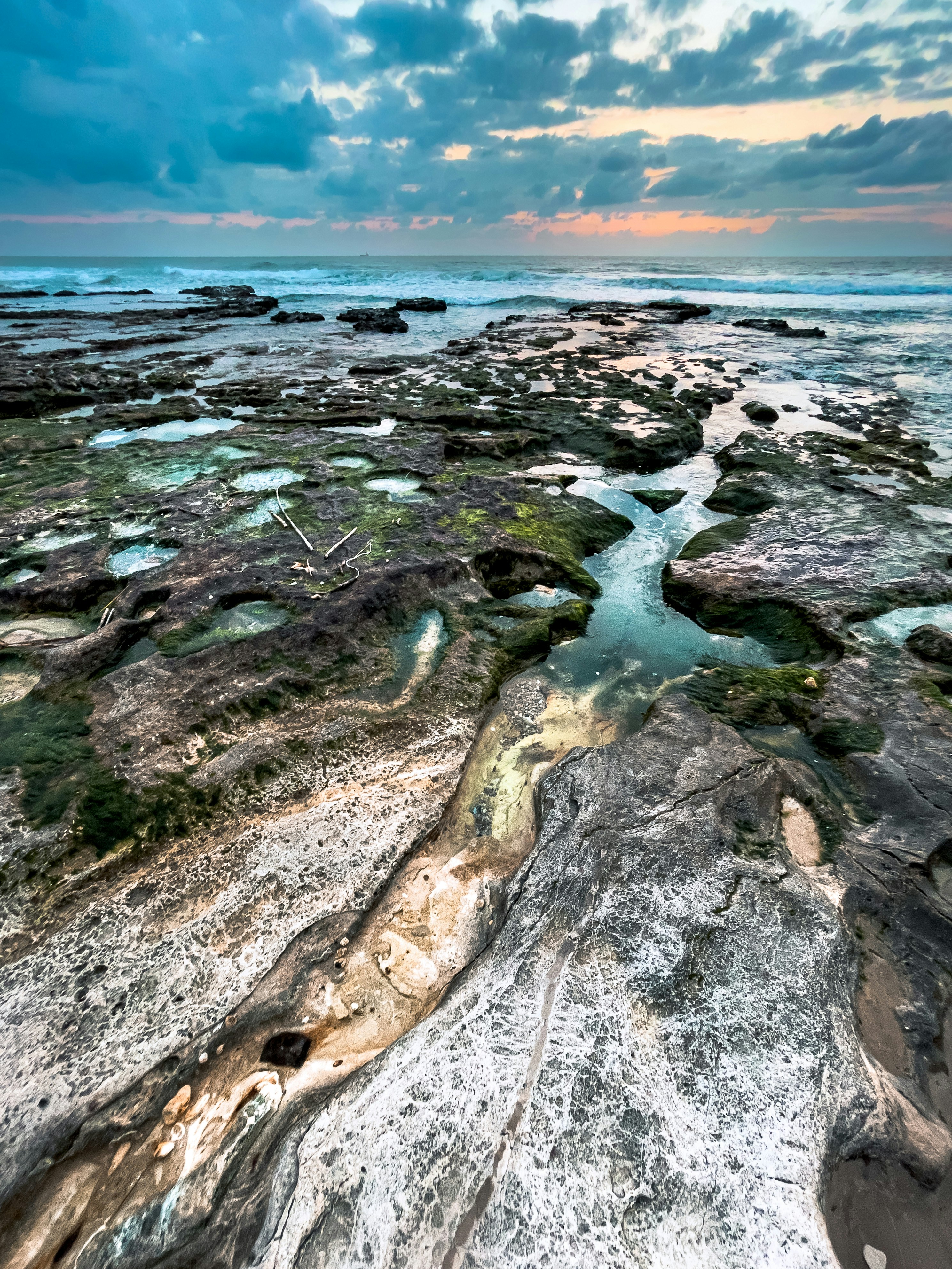 a river running through a rocky beach under a cloudy sky
