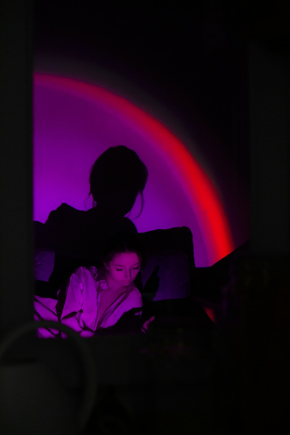 a woman laying in bed with a purple light behind her