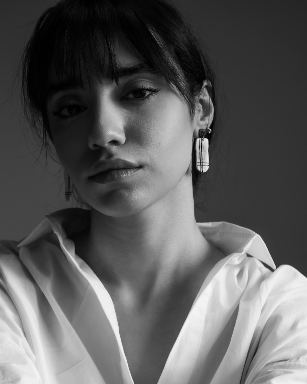 a woman in a white shirt is wearing a pair of earrings
