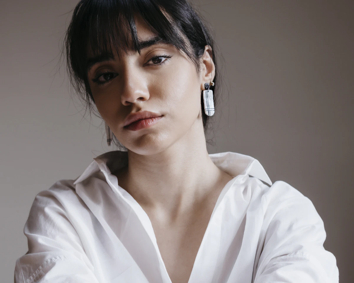 Adult woman in a white shirt wearing a long crystal drop earring