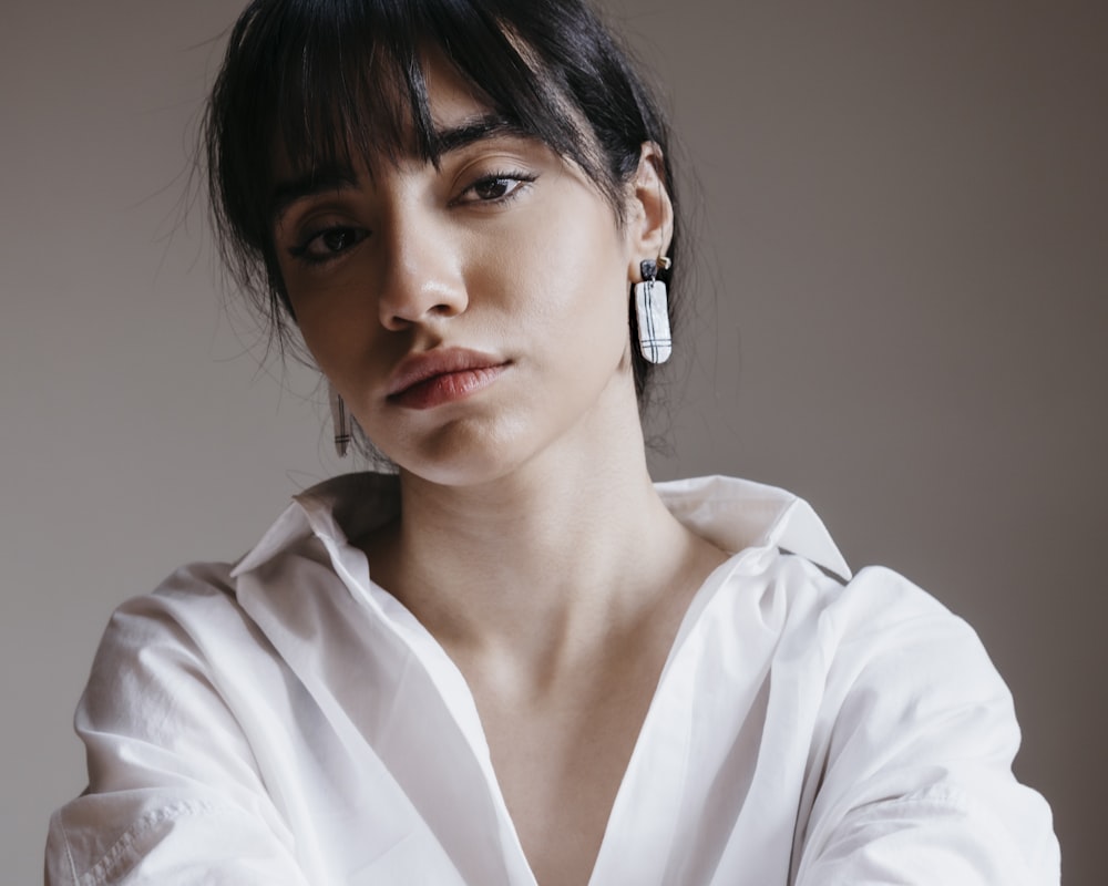 a woman wearing a white shirt and earrings
