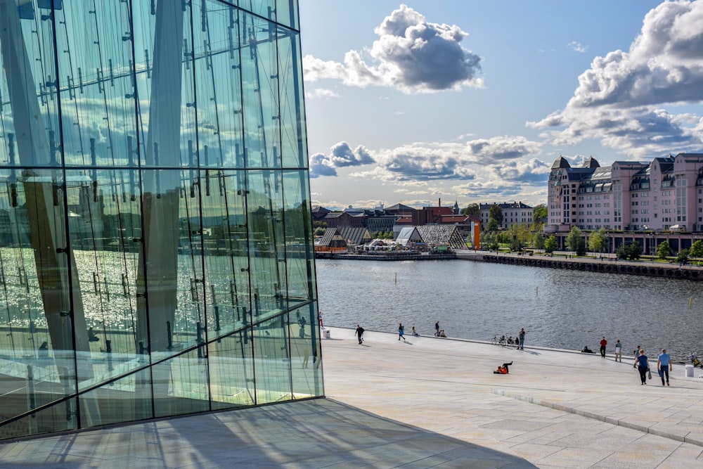 a large glass building next to a body of water