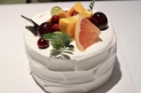 A beautifully decorated cake with fresh fruit toppings on a wooden table.