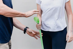 A wellness professional guiding a client through gentle rehabilitation exercises at home.