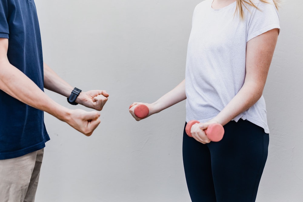 a man and a woman standing next to each other holding dumbs