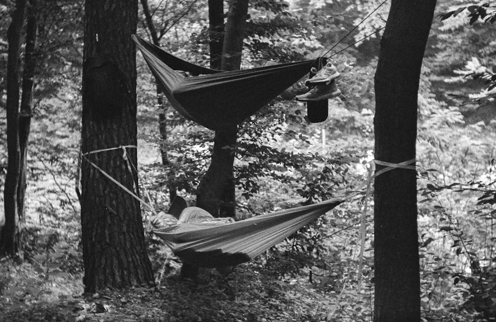 a person laying in a hammock in the woods