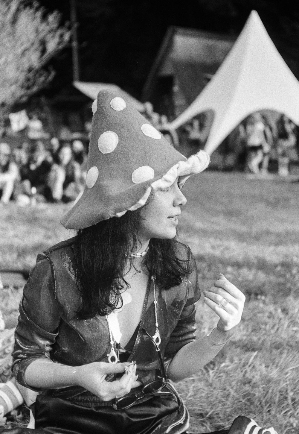 a woman sitting on the ground wearing a polka dot hat