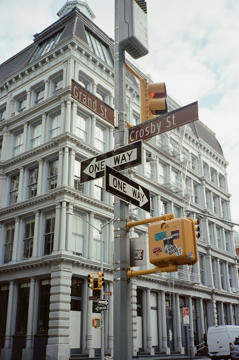 a pole with street signs and traffic lights in front of a building