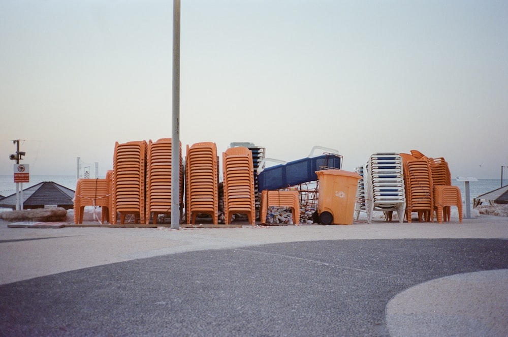 a row of orange chairs sitting on top of a parking lot