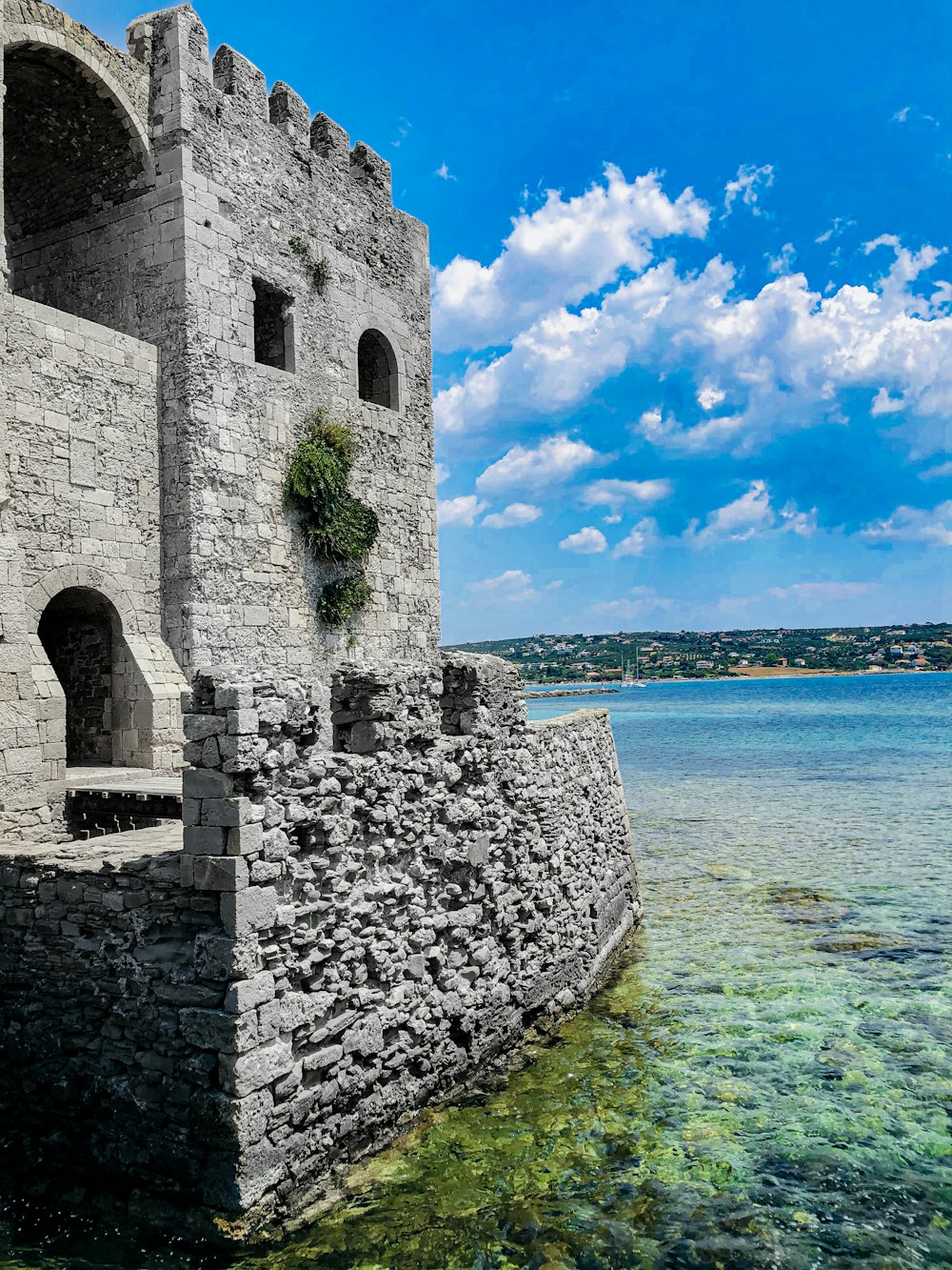 a stone wall next to a body of water