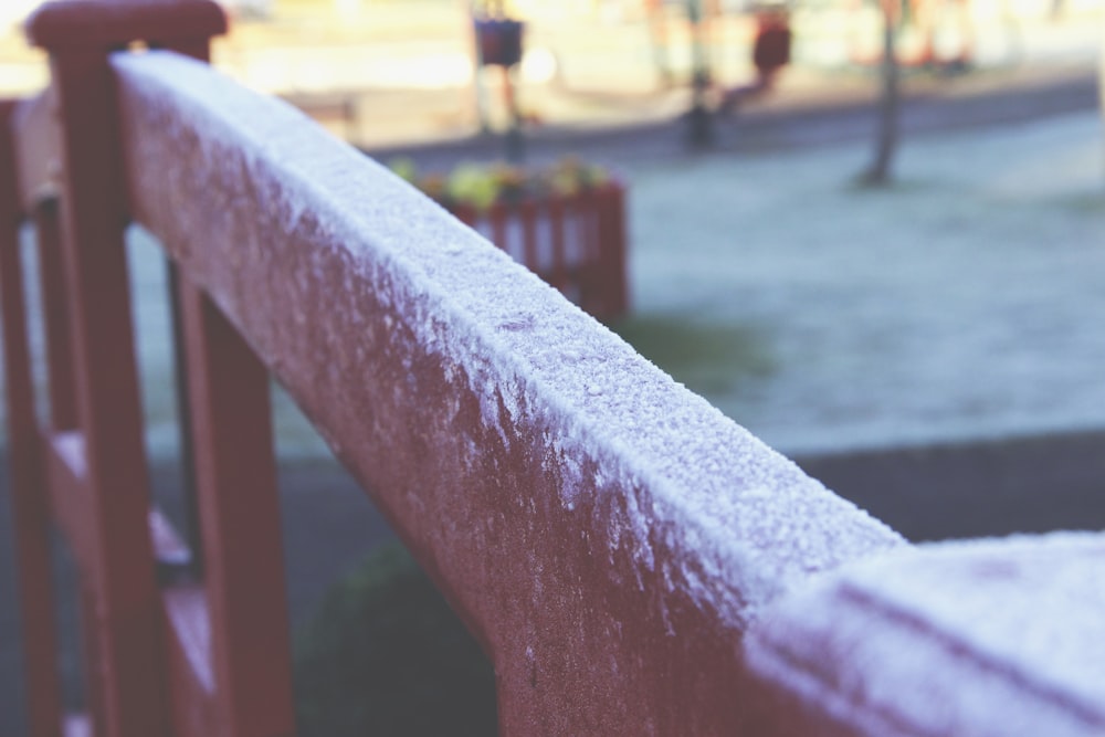 a close up of a bench with snow on it