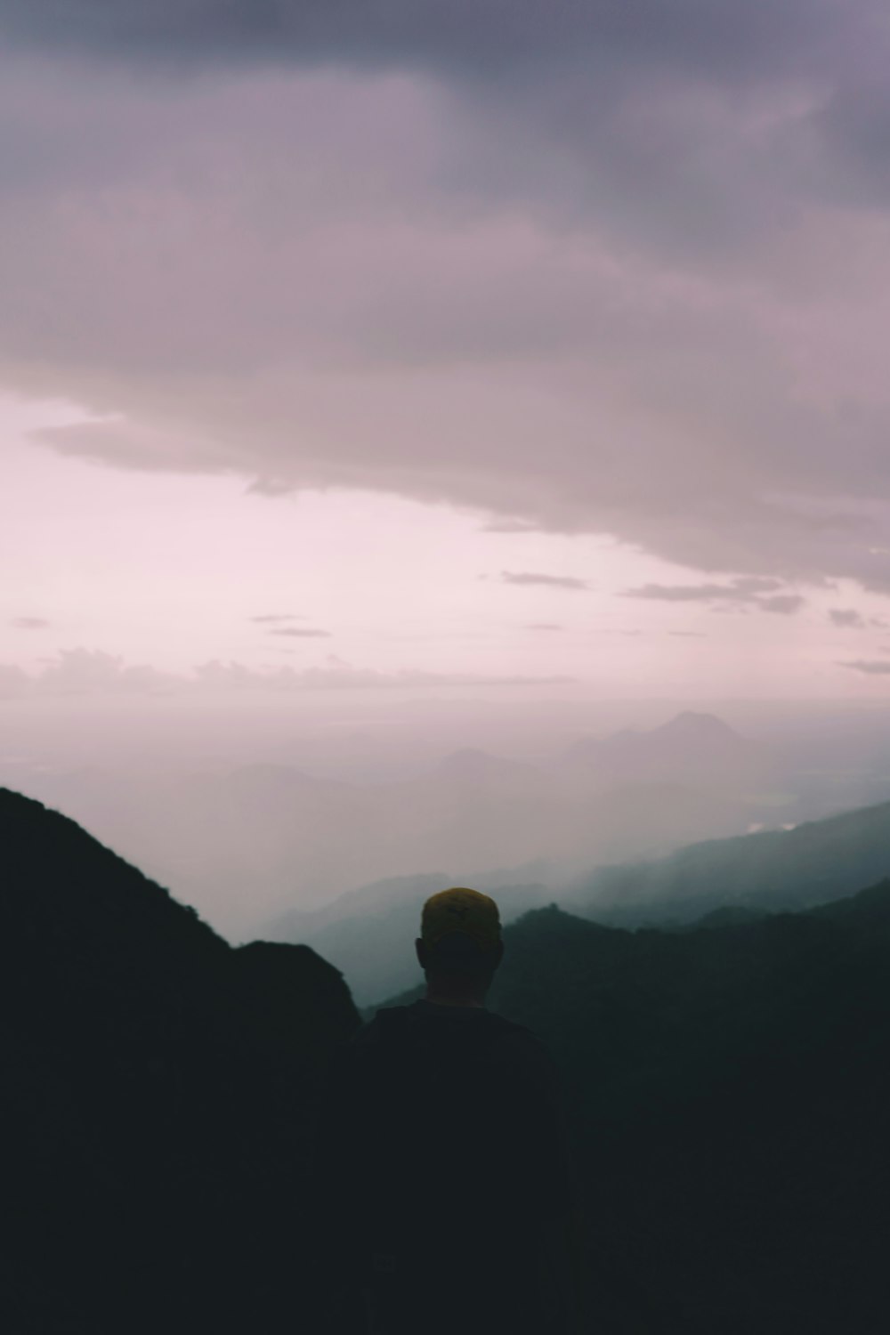 a man standing on top of a mountain under a cloudy sky