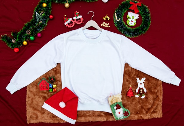 A cheerful display of colorful ugly Christmas sweaters, modern t-shirts, and cozy hoodies arranged on a rustic wooden table.