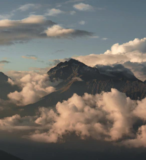 A mountain peak surrounded by soft, fluffy clouds.