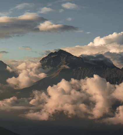 A mountain peak surrounded by soft, fluffy clouds.