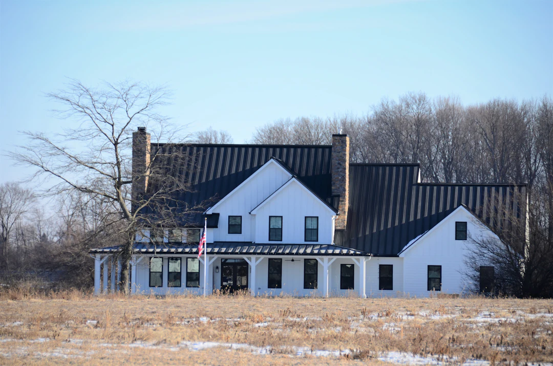 Two-story white house with a dark shingle roof and landscaped yard