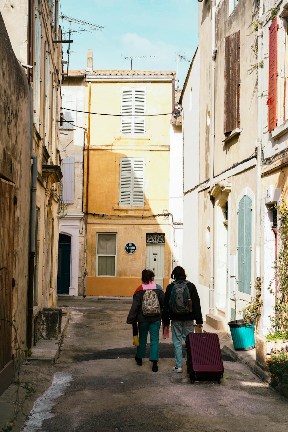 um casal de pessoas andando por uma rua com bagagem