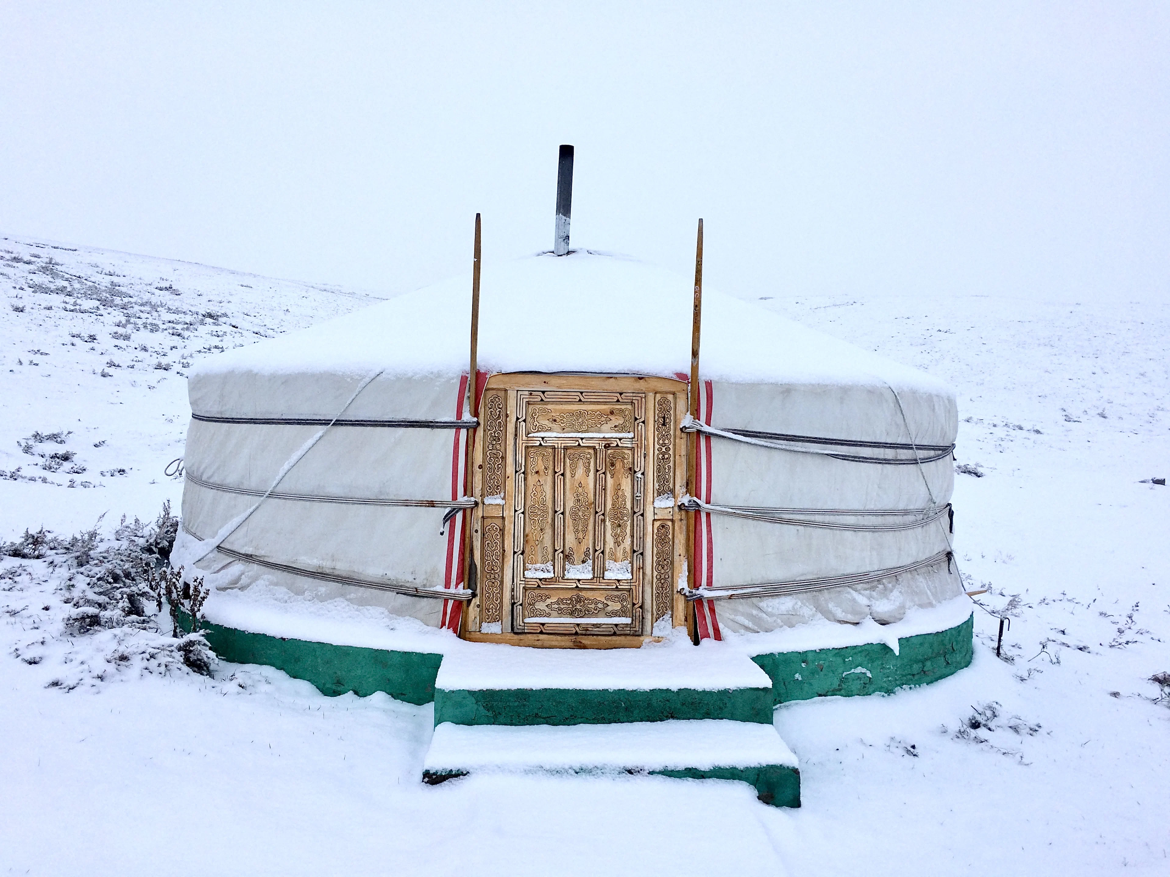 A ger with a painted door half buried in snow