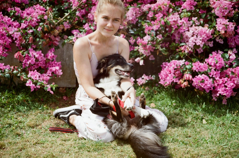 a woman sitting in the grass with a dog