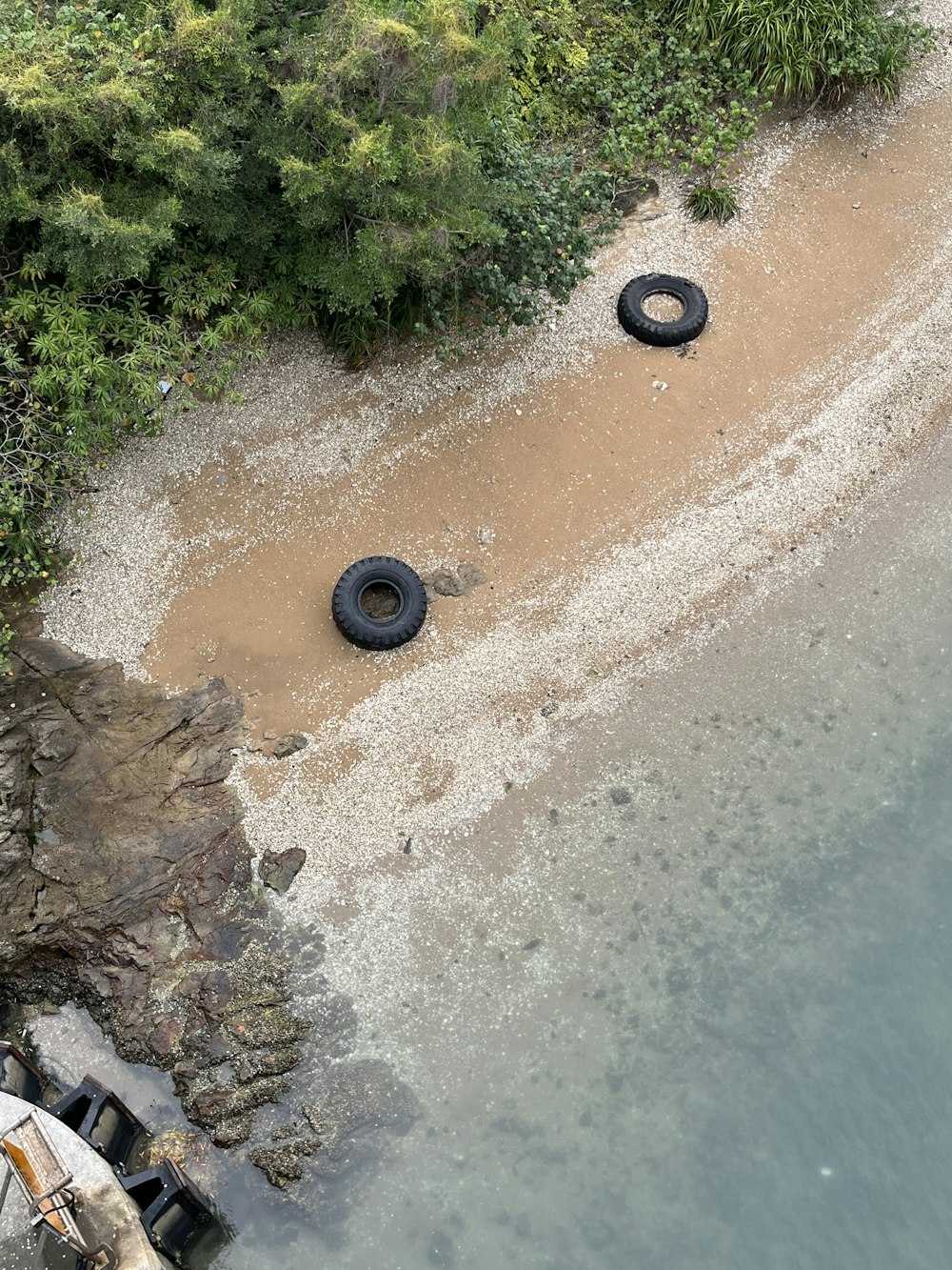 an aerial view of a beach with two tires in the sand