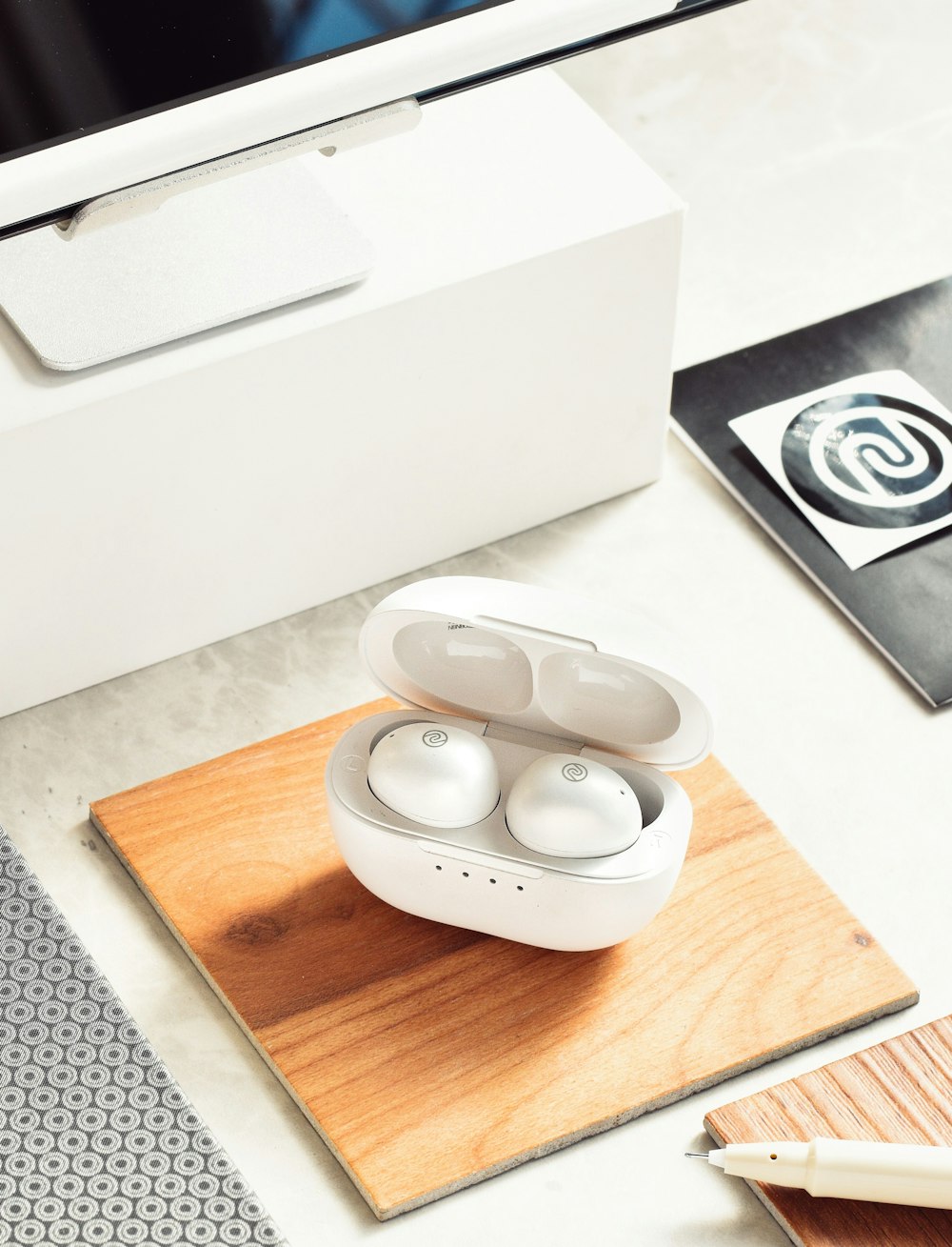 a pair of earbuds sitting on top of a wooden coaster