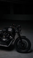A sleek black motorcycle parked under moody lighting, emphasizing its design details.