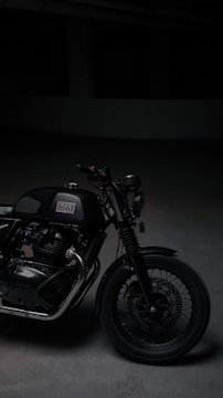 A sleek custom motorcycle with polished chrome and matte black finish parked against a dark urban backdrop.
