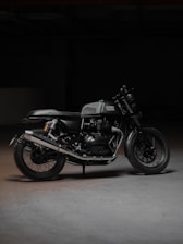 A sleek black motorcycle parked inside a minimalist, industrial-style garage space with warm lighting.