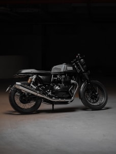 A sleek black motorcycle parked inside a minimalist, industrial-style garage space with warm lighting.