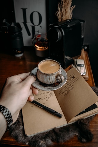 a person holding a cup of coffee on top of a book