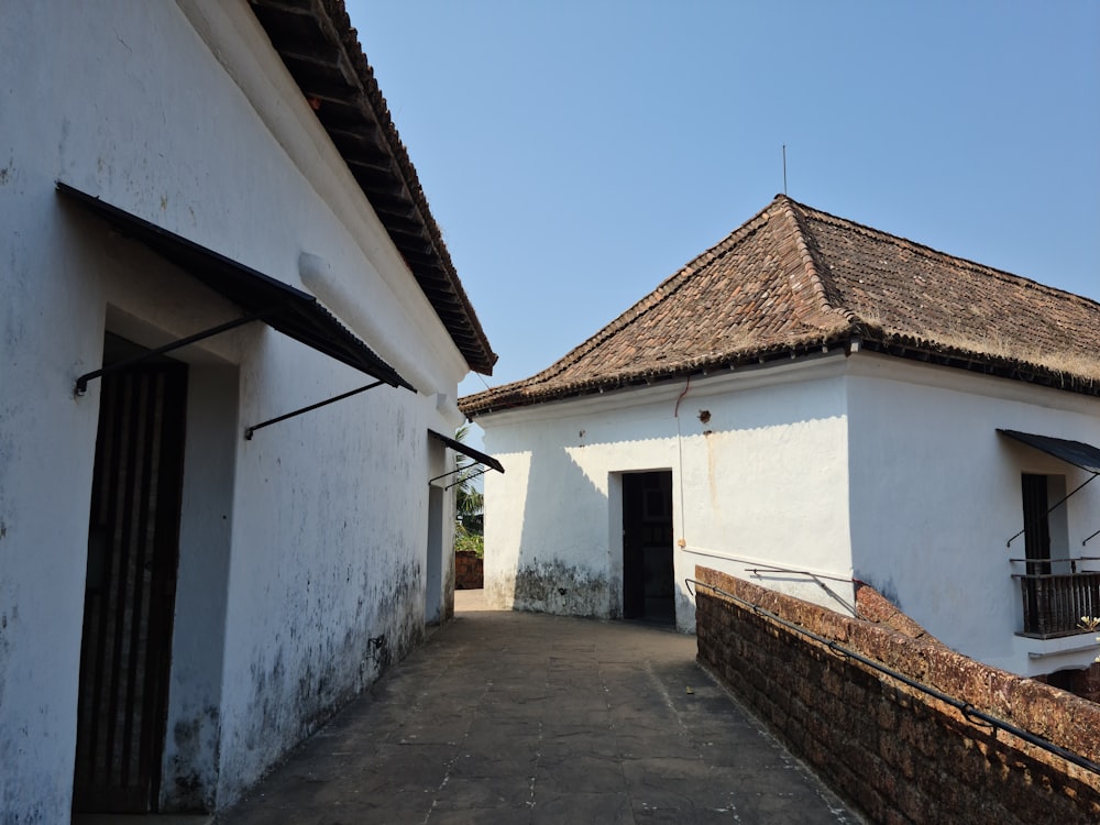 a white building with a brown roof next to a brick wall