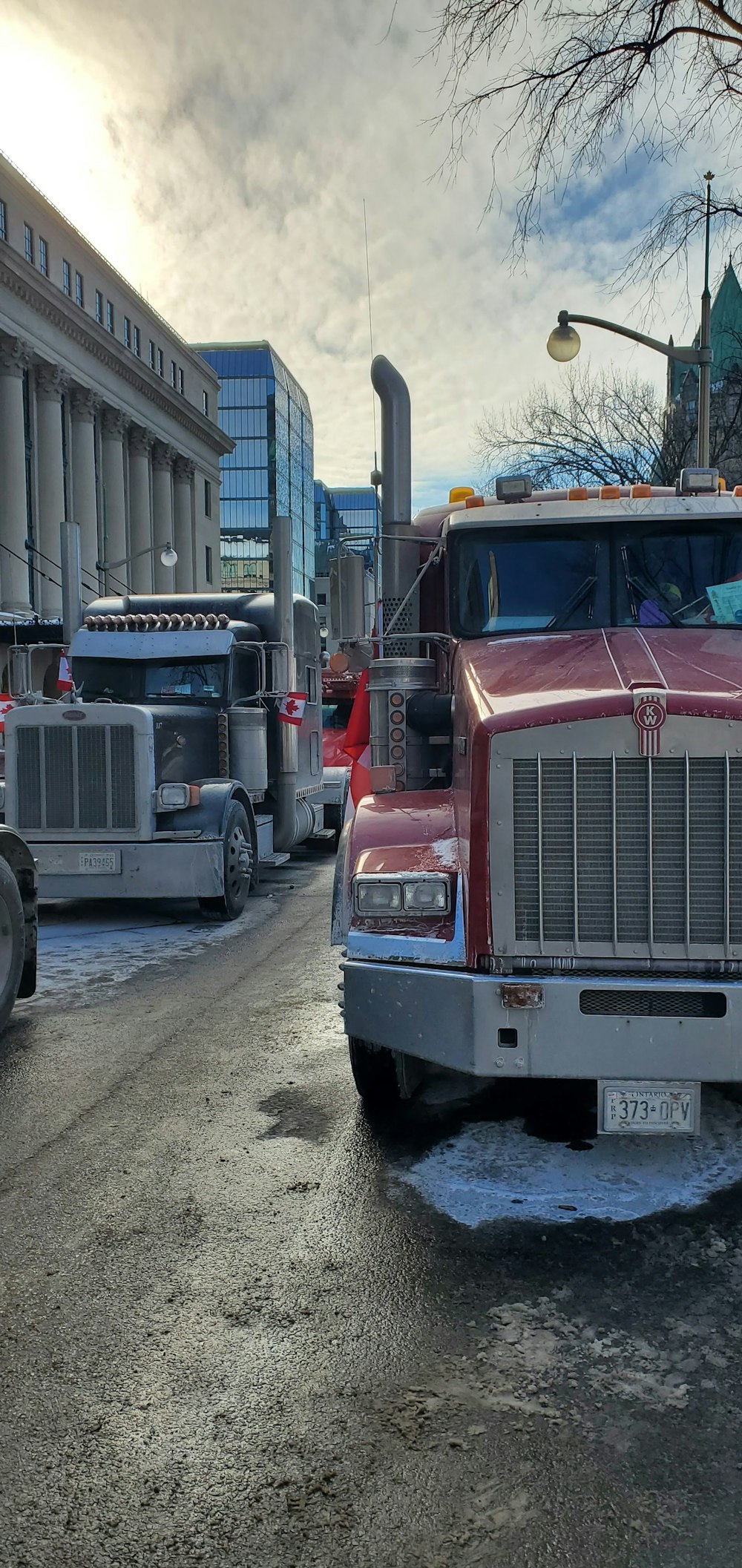a red semi truck driving down a street next to a tall building